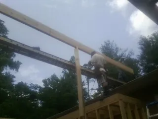 Carpenter setting a ridge beam over a new addition frame — Ice Dam Removal by Roofing Brothers in Deming