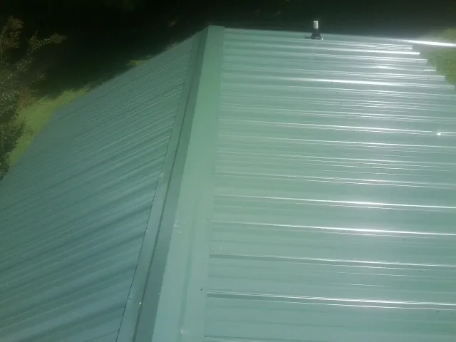 New green metal panels meeting at the ridge of a roof — Flat Roof Repair work by our crew in Deming