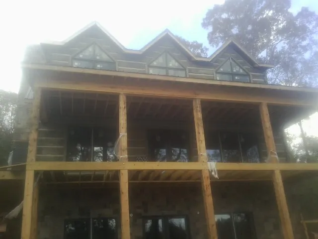 Dormers and porch framing on a large log home under construction — Roof Coating work by our crew in Deming