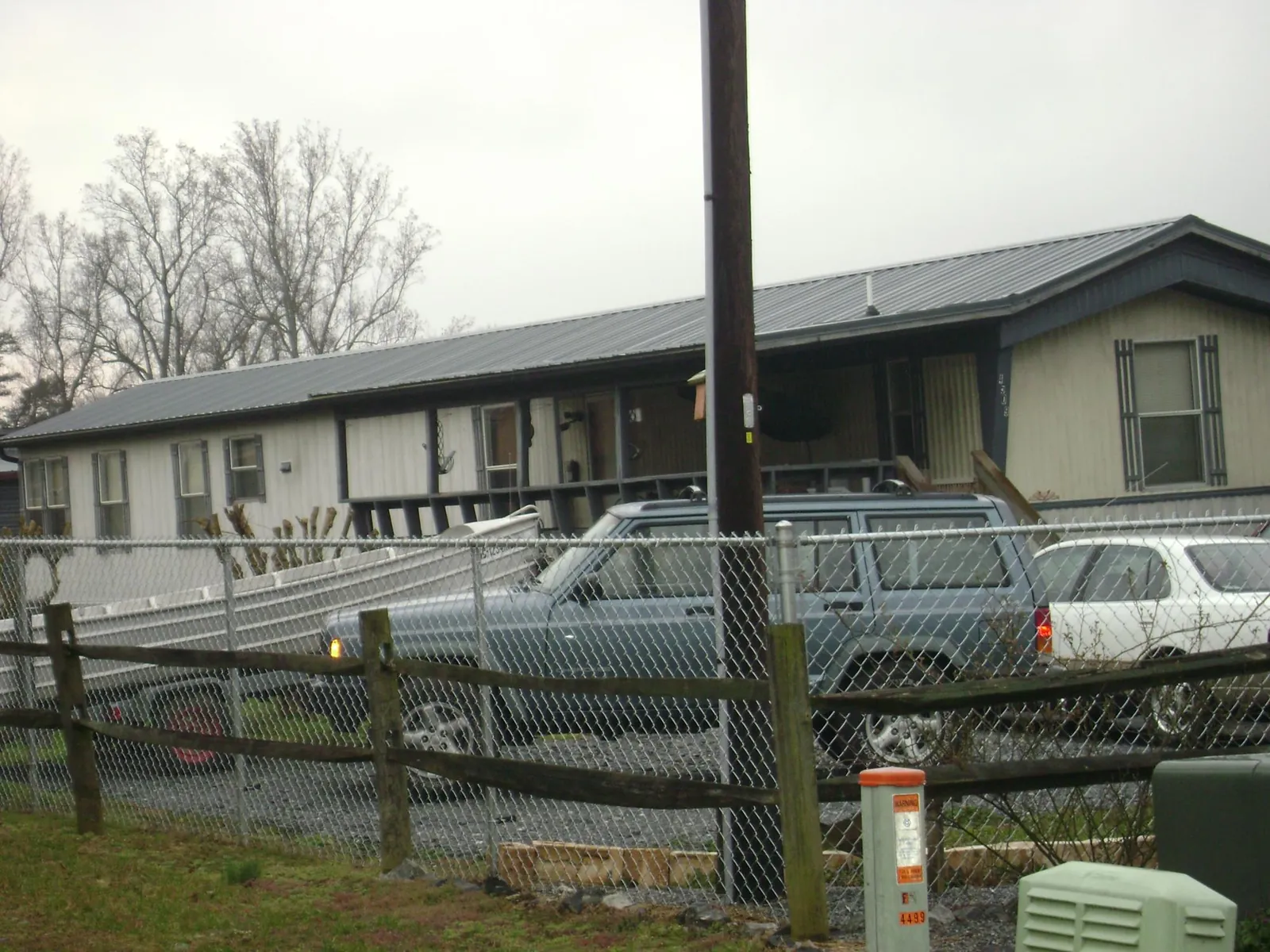 Dark metal roof on a long single story building behind a chain link fence in Deming