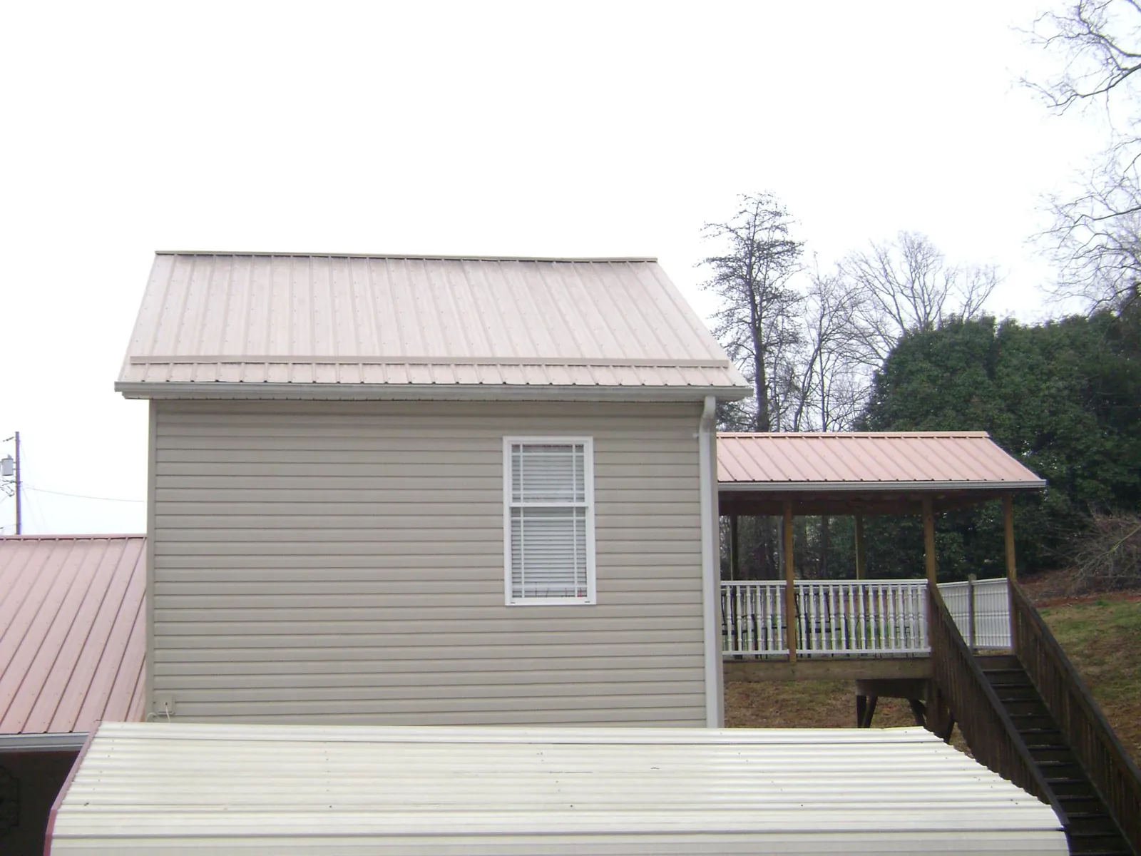 Tan metal roofs on a two story addition and attached porch, from a Roof Replacement job in Deming